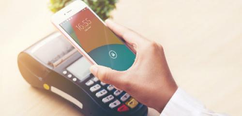 biały smartfon trzymany w dłoni przyłożony do terminalu płatniczego - promocja ING Banku Śląskiego i karty Mastercard