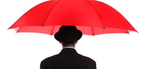 mężczyzna w czarnym meloniku i garniturze stoi pod czerwonym parasolem
