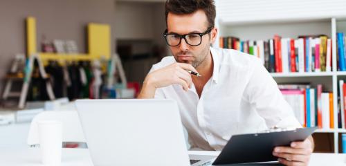Mężczyzna siedzi przy komputerze i zastanawia się nad kosztami kredytu gotówkowego na 10 tys. zł