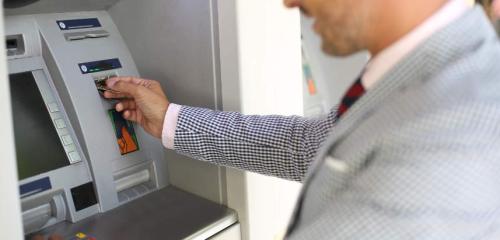 człowiek wypłacający pieniądze z bankomatu