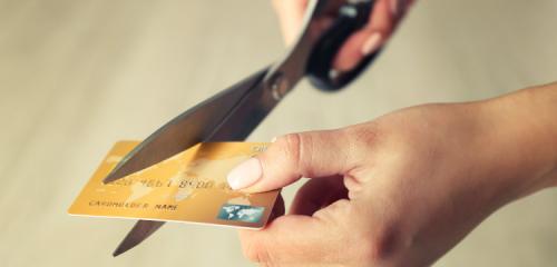 damskie dłonie trzymające nożyczki i przecinające kartę kredytową