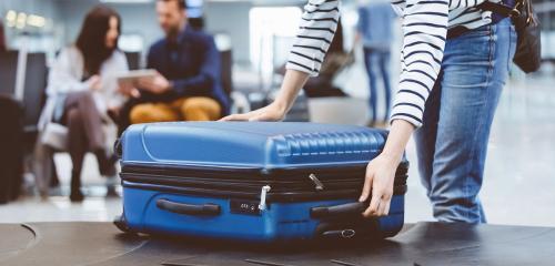 Dziewczyna na lotnisku odbiera walizkę - wraca do pracy za granicą