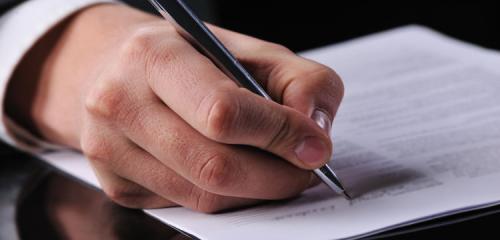 mężczyzna podpisujący długopisem dokument