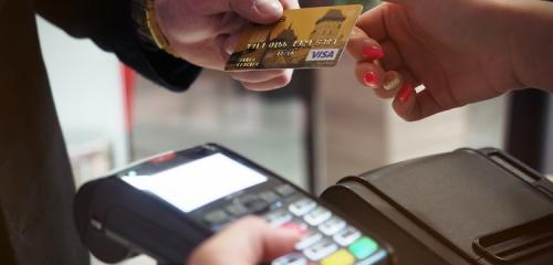 dwie osoby podają sobie kartę kredytową przed płatnością w terminalu