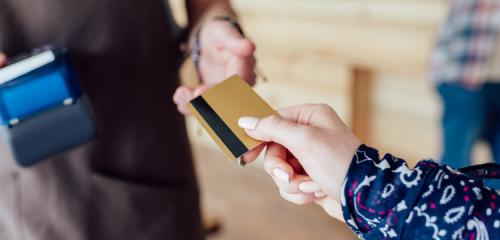 kobieca dłoń przekazująca kartę kredytową mężczyźnie z terminalem płatniczym
