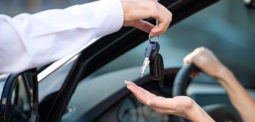 zbliżenie na dłoń sprzedawcy samochodów przekazującą kluczyki do samochodu na dłoń kobiety