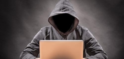 mężczyzna w kapturze z ukrytą twarzą stara się wyłudzić pożyczkę przez internet