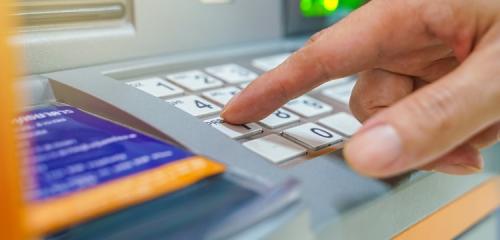 palec wpisujący pin na klawiaturze bankomatu