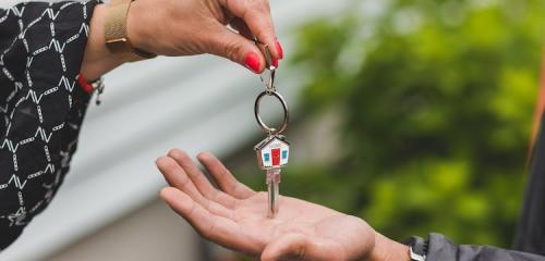 Kobieca dłoń przekazująca klucze do mieszkania na dłoń mężczyzy po ustanowieniu hipoteki