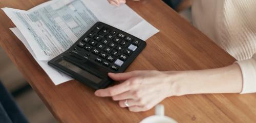 kobieta z kalkulatorem i dokumentami dbająca o terminową spłatę kredytów