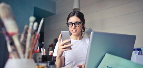 kobieta w pracowni z laptopem i smartfonem sprawdzająca przelew w Santander Bank Polska