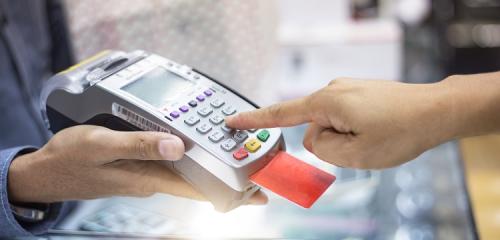 Osoba płacąca kartą wsuniętą do terminala płatniczego