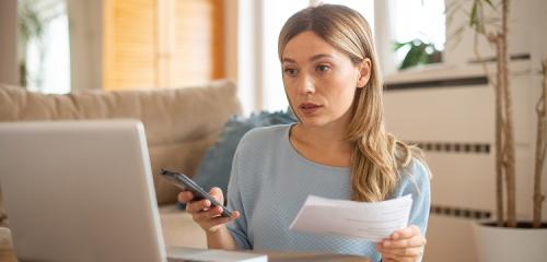 Młoda kobieta sprawdza rachunki i liczy stan swoich finansów na komputerze