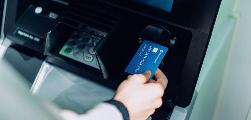 osoba sprawdzająca, jak wypłacić pieniądze z bankomatu