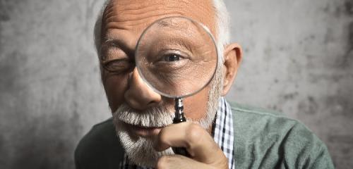 Starszy mężczyzna spogląda przez lupę - weryfikacja KRD