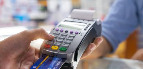 mężczyzna wpisujący kod PIN na klawiaturze terminala podczas płatności kartą