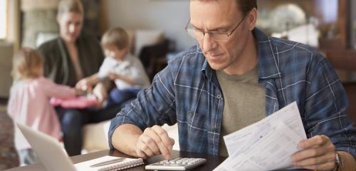 Mężczyzna spłacający kredyt mieszkaniowy oblicza na kalkulatorze korzyści z wakacji kredytowych 2024