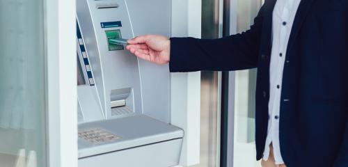 Mężczyzna korzysta z bankomatu za pomocą karty