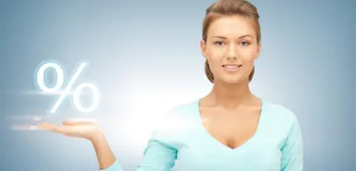 kobieta w niebieskim sweterku podtrzymuje na dłoni biały symbol procenta