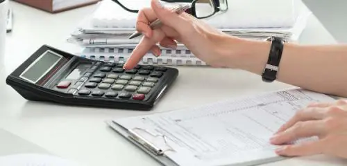 kobieta przy biurku z kalkulatorem