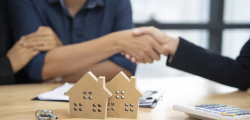 Kobieta i mężczyzna ściskają sobie dłonie po podpisaniu umowy o kredyt hipoteczny