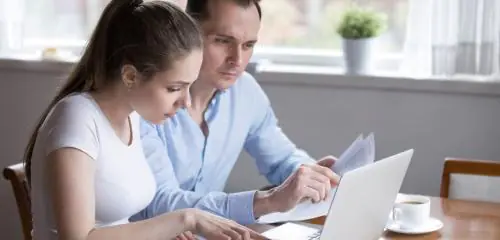 Kobieta i mężczyzna sprawdzają na komputerze jak odzyskać hasło do bankowości internetowej