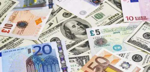 Waluty wielu krajów, m.in. dolary amerykańskie, rozłożone na biurku