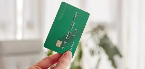 Kobieta trzymająca w dłoni zieloną kartę kredytową
